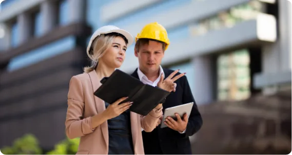 Civil engineers with helmets reviewing plans – MSc Civil Engineering in UK