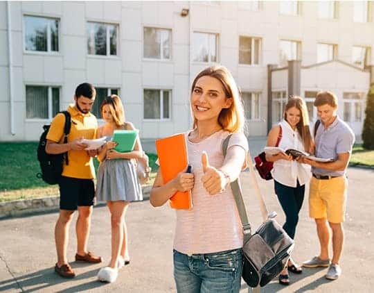 A student standing with books in front of a university campus, guided by Overseas Education Consultants in Kerala for study abroad opportunities.